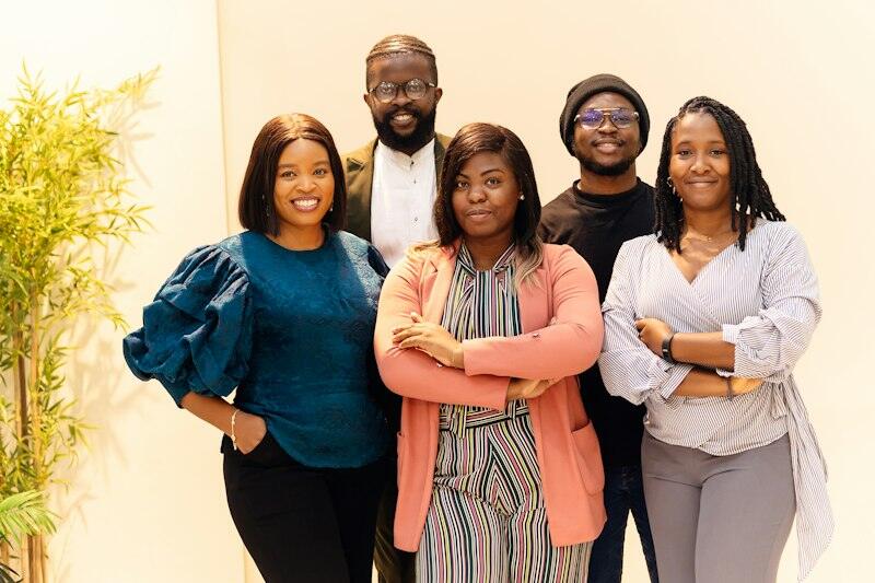 A smiling team of five colleagues standing together